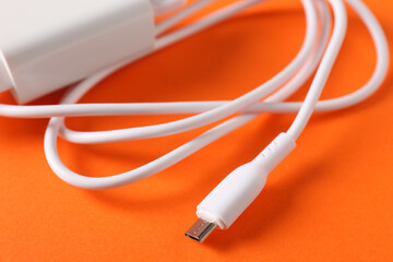 USB power adapter with charge cable on orange background, closeup