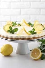 Delicious lemon cheesecake with mint and fresh fruits on white wooden table, closeup