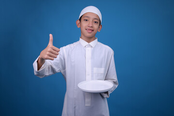 Portrait Of Young Asian Muslim Boy Giving Thumb Up While Holding Empty White Plate