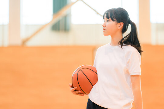 体育館でバスケットボールを持つ体操着姿の女子中学生・女子高生
