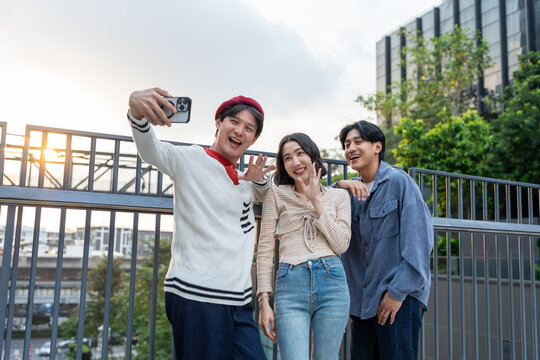 Diverse Asian young friends using phone video call outdoors in park. - Powered by Adobe