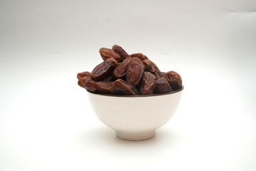 Dried dates fruits in ceramic bowl isolated on white background.