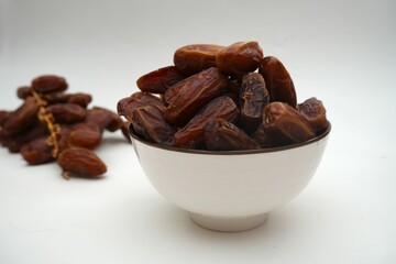 Dried dates fruits in ceramic bowl isolated on white background.
