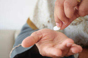 Person takes medication from hand in indoor setting