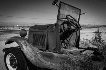 Left side view of an antique Model A truck abandoned in the desert.