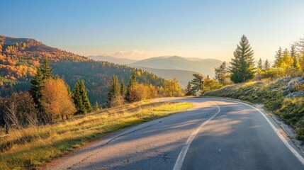 Obraz premium Winding mountain road framed by vibrant autumn foliage and clear skies