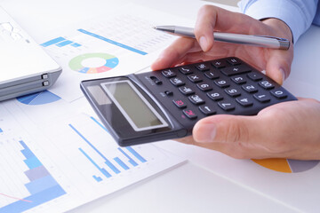 電卓でビジネス関係の計算をしている男性