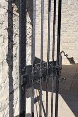 ANCIENNE PORTE EN FERRONNERIE NOIRE ATTACHEE A UNE STRUCTURE EN PIERRE