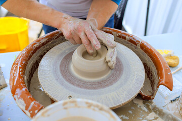 Potter skillfully molds wet clay on pottery wheel in creative art studio