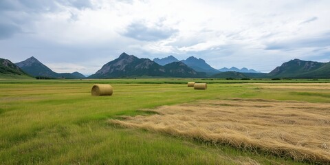 Obraz premium This breathtaking image presents a picturesque landscape with rolling mountains and hay bales scattered across vibrant green fields, capturing the beauty of nature and tranquility.
