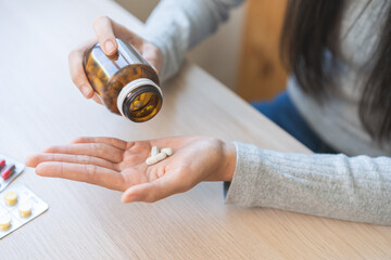 Sick ill asian young woman, girl hold tablet pill on hand pour capsule from medication bottle,...