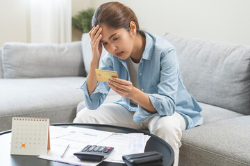 Debt and financial concept, stressed asian young woman have a headache while sitting on sofa...