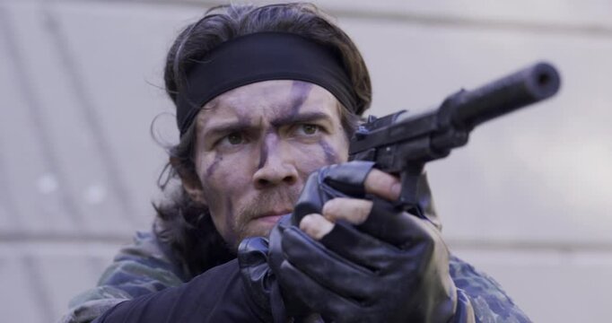 Spy holding a gun with silencer deciding where to shoot, close up