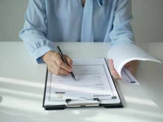 Fototapeta premium Young businesswoman holds a resume and evaluates it. Views the personal history of job applicants. Recruitment concept