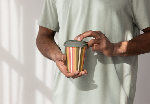 Faceless Man carefully holds a disposable takeaway paper cup with a lid,  PSD template mockup ready for your Design