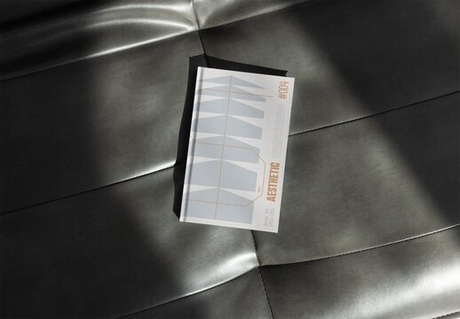book cover mockup rests on a smooth leather surface, ideal for showcasing design concepts and layouts.