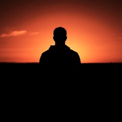 Dramatic Black and White Silhouette of Lone Figure Against Vibrant Sunset
