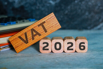 VAT 2026 on wooden cubes with calculator and notepad.