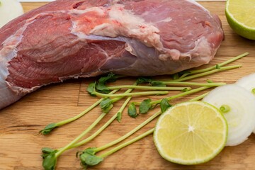 Fresh raw beef with onion and lime on a wooden cutting board.