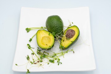 Fresh avocado slices with microgreens on a white plate. Avocado halves. Healthy food.