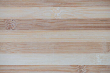 Bamboo board striped texture close-up. Surface of flat bamboo board composed of alternating planks of of light and dark tones, pattern, background, high resolution.