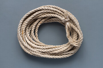 A coil of rope on a gray background. Yellow classic rope.