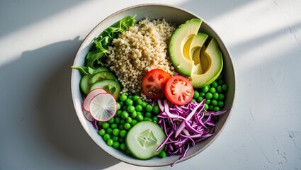 nutritious plant-based lunch bowl featuring quinoa, avocado, tomatoes, cucumber, red cabbage, green peas, and radish. Aerial view.