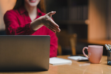 Businesswoman offering handshake in home office after successful online meeting