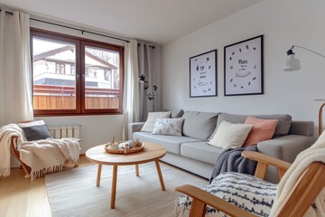 Cozy living room with large window overlooking snowy landscape. Light, airy, and warm interior design featuring a comfortable sofa, armchairs, and wooden coffee table.