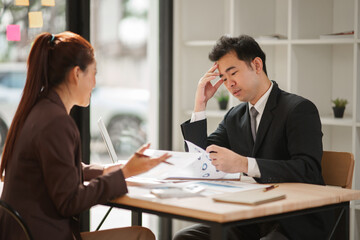Male and female business people working in finance in an office.