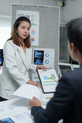 Businesswoman showing charts and graphs to businessman in meeting room