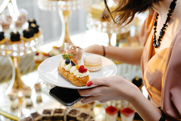 Woman holding a plate of dessert while standing near a candy bar