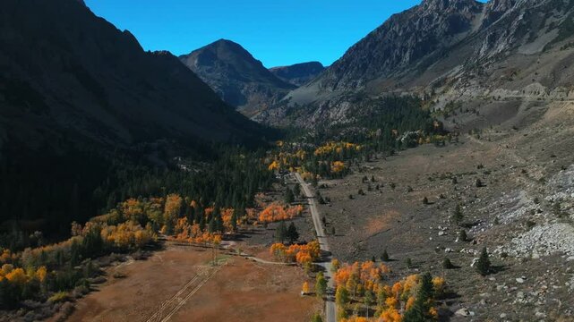 West Portal Entrance rugged Mountains Lee Vining Tioga Pass Road Yosemite National Park California aerial drone Ansel Adams Wilderness Big Oak Flat fall yellow orange Aspen Trees blue skies backwards