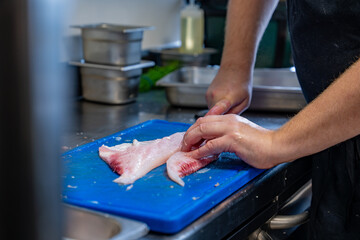 Focus sur un chef étoilé qui est en train de découper le poisson pour en faire des filets, mettant en valeur la préparation culinaire du fruit de mer. Découpe du Turbo.