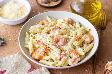 Penne pasta in creamy garlic sauce with shrimps and cheese. Italian food.