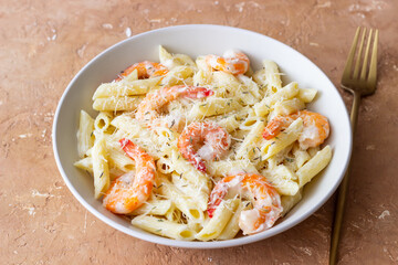Penne pasta in creamy garlic sauce with shrimps and cheese. Italian food.
