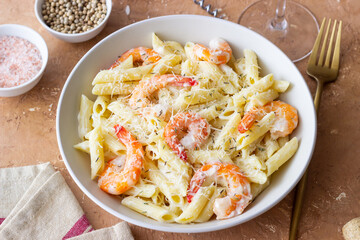 Penne pasta in creamy garlic sauce with shrimps and cheese. Italian food.