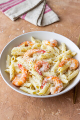 Penne pasta in creamy garlic sauce with shrimps and cheese. Italian food.