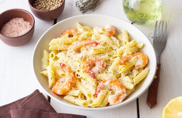 Penne pasta in creamy garlic sauce with shrimps and cheese. Italian food.