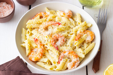 Penne pasta in creamy garlic sauce with shrimps and cheese. Italian food.
