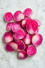 Vibrant red radish slices are elegantly spread on a pristine white surface, showcasing their rich color and smooth texture, ideal for fresh dishes and creative culinary presentations