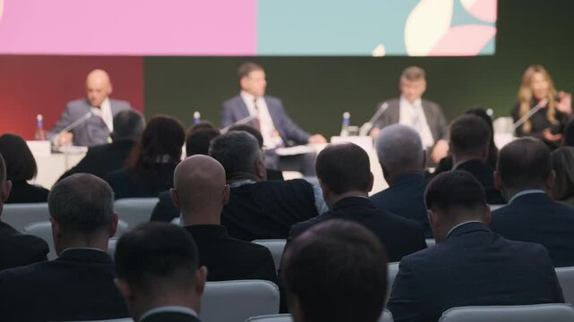 Attendees at organized business conference watching panel of speakers discussing professional topics and challenges