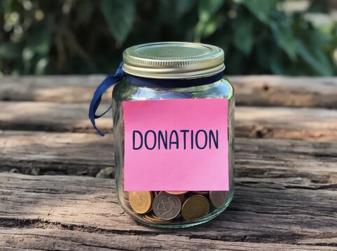 Donation jar with coins on a wooden table