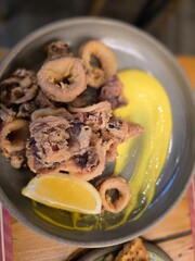 Crispy calamari served with lemon and a vibrant sauce in a cozy restaurant setting