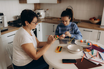 Mother and Daughter Painting Eggs Together in a Bright Modern Kitchen