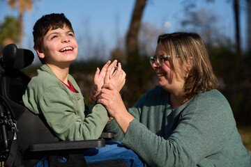 Therapist assisting child with disability in wheelchair outdoors - cerebral palsy concept
