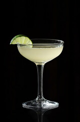 A Gimlet cocktail in a coupe glass, pale greenish gin and lime juice mix isolated on a black background