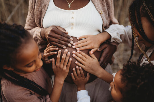 Close up mix race children hands on black pregnant mom belly