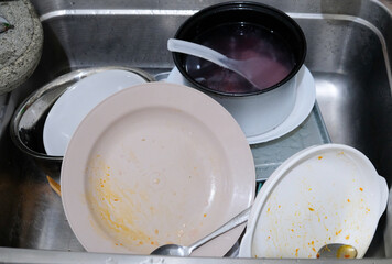 Mess in the kitchen, lot of dirty dishes in the sink.