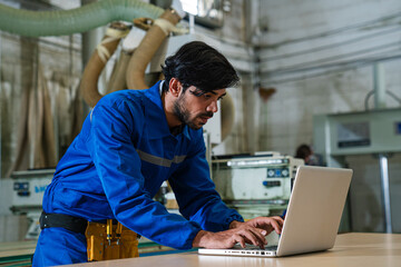 Technician using laptop checking and repair pressing metal machine